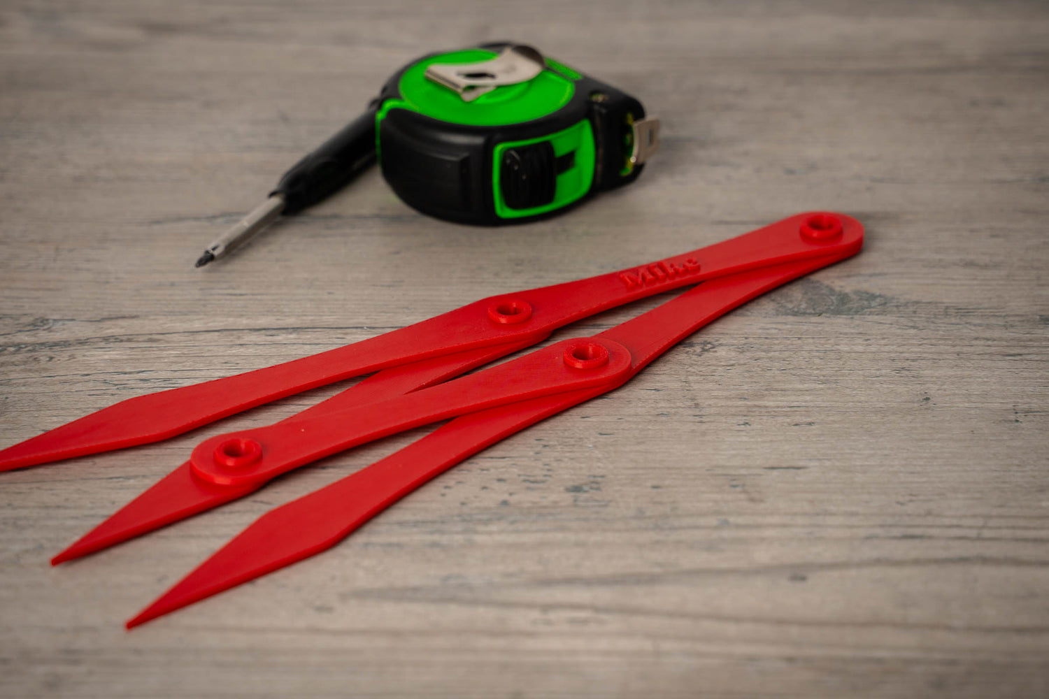 Red plastic tools and a tape measure on a wooden surface
