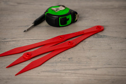 Red plastic tools and a tape measure on a wooden surface